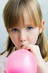 Cute Little  Girl Inflating A Pink Balloon In The Kitchen Stock Photo