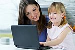 Mother And Daughter Using Laptop In The Kitchen Stock Photo